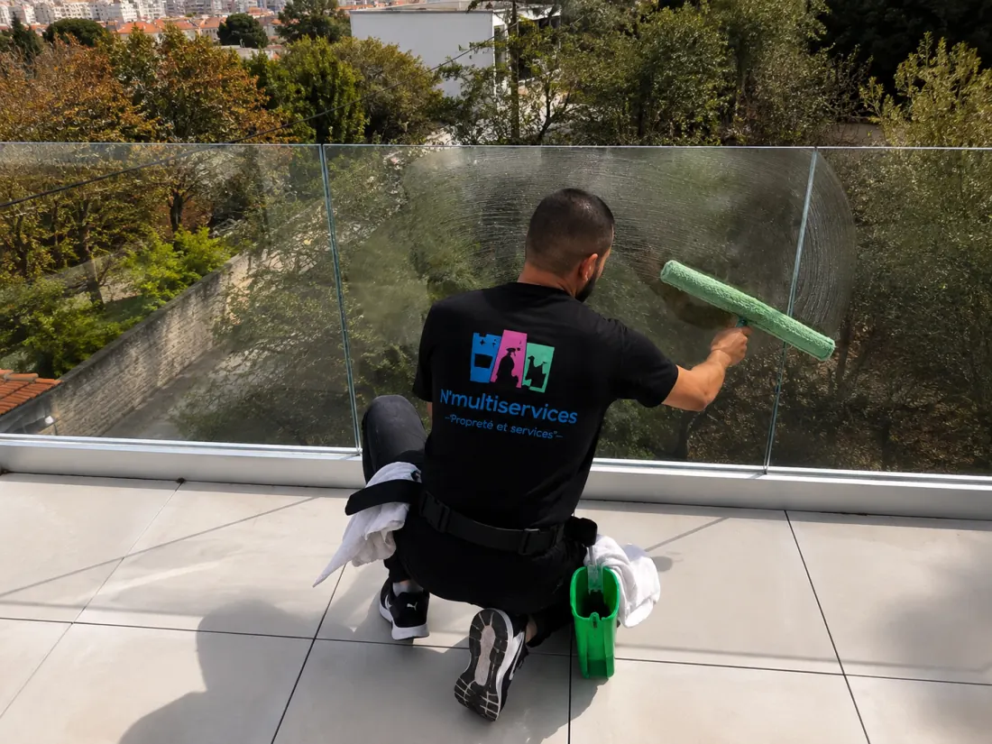 Agent N’Multiservices nettoyant une paroi vitrée en hauteur